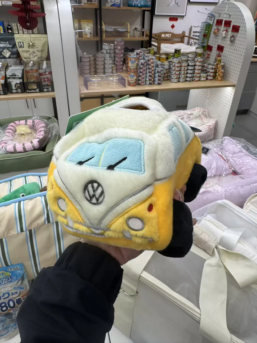The yellow camper bus plush held up in a pet store