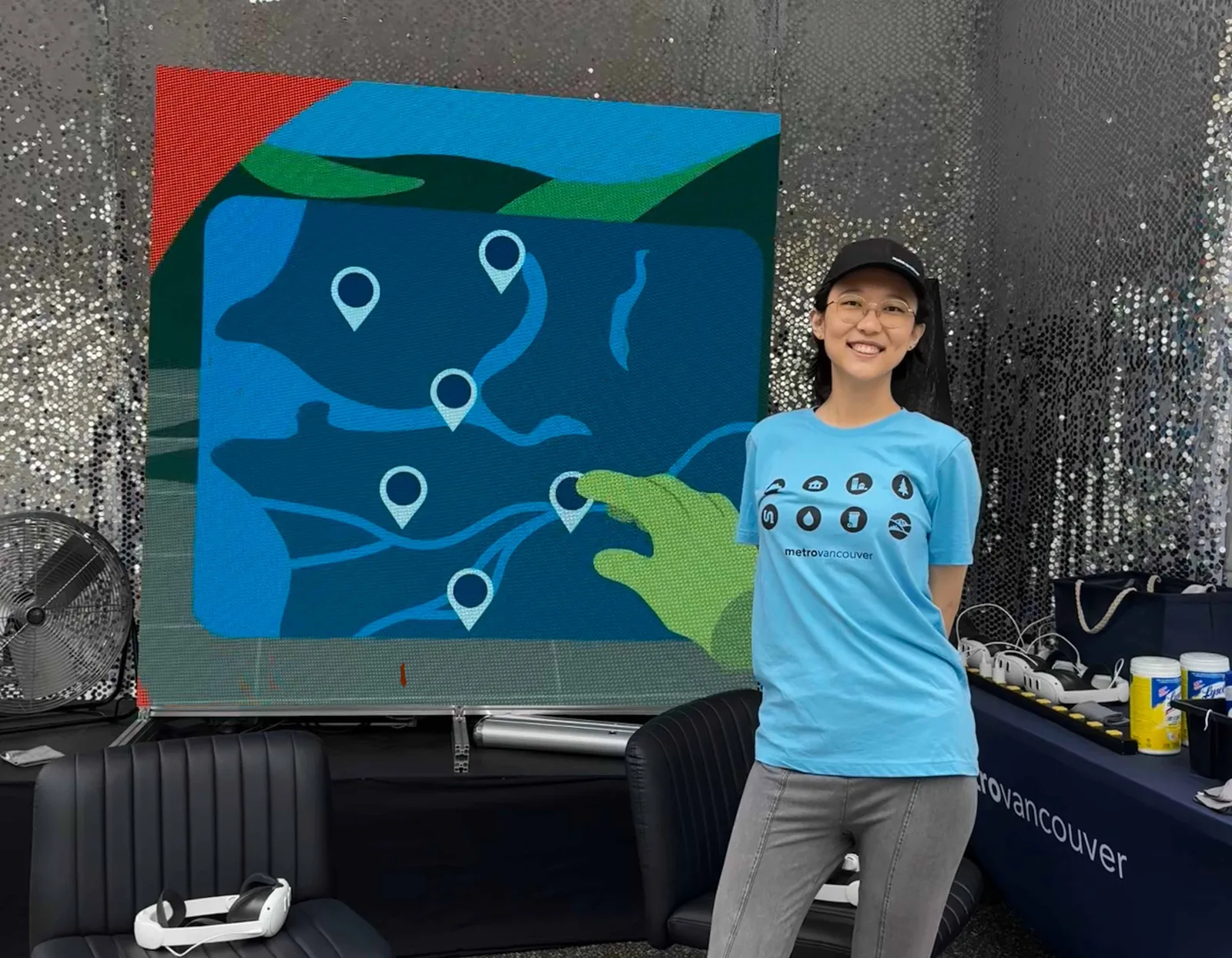 Nicole at a booth in front of a large Metro Vancouver map
